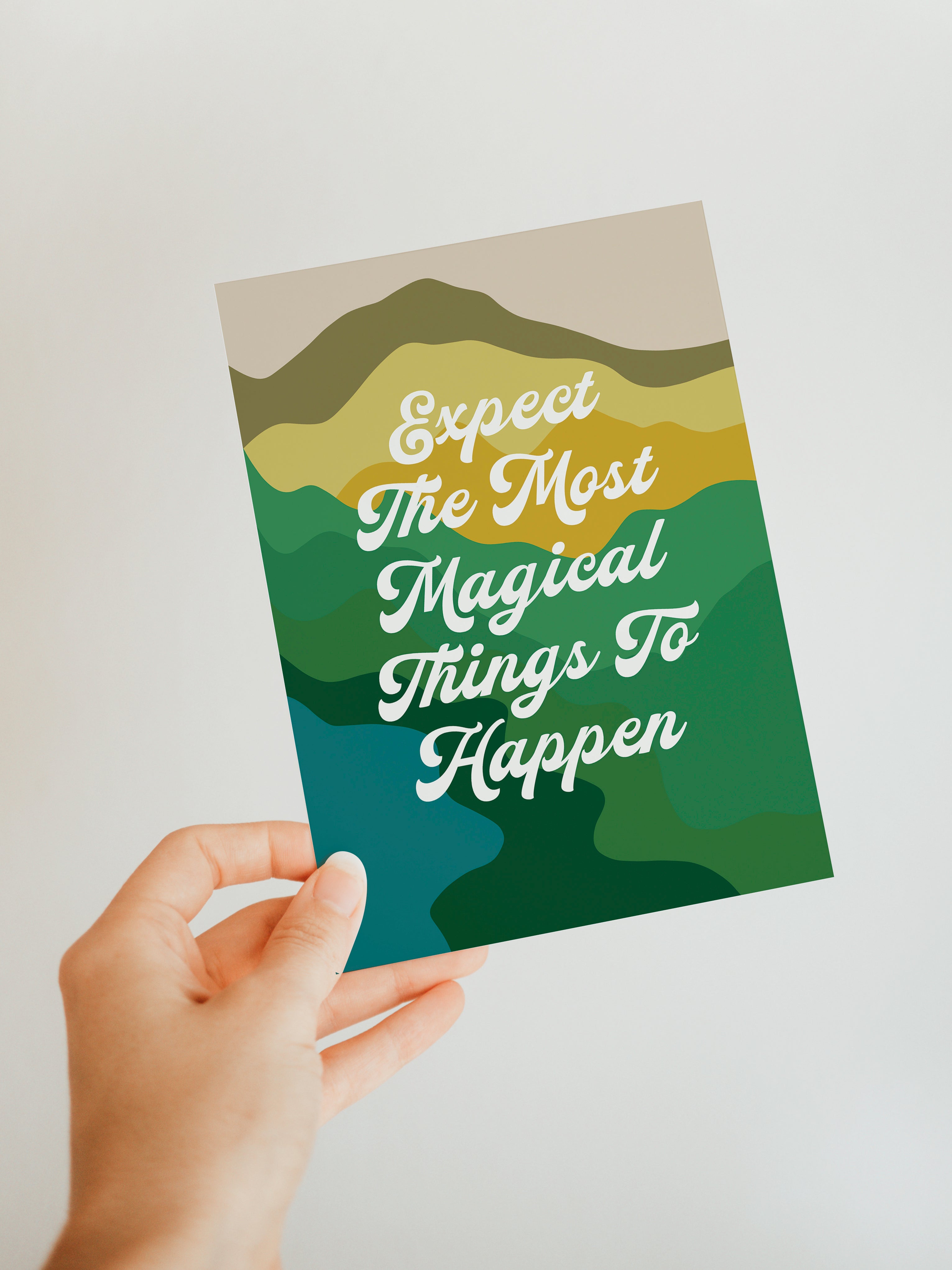 Blank note card with the text 'Expect Magical Things To Happen' printed in serif font, shown on a neutral surface.