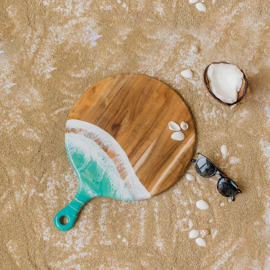 Wooden paddle with green handle on sandy surface