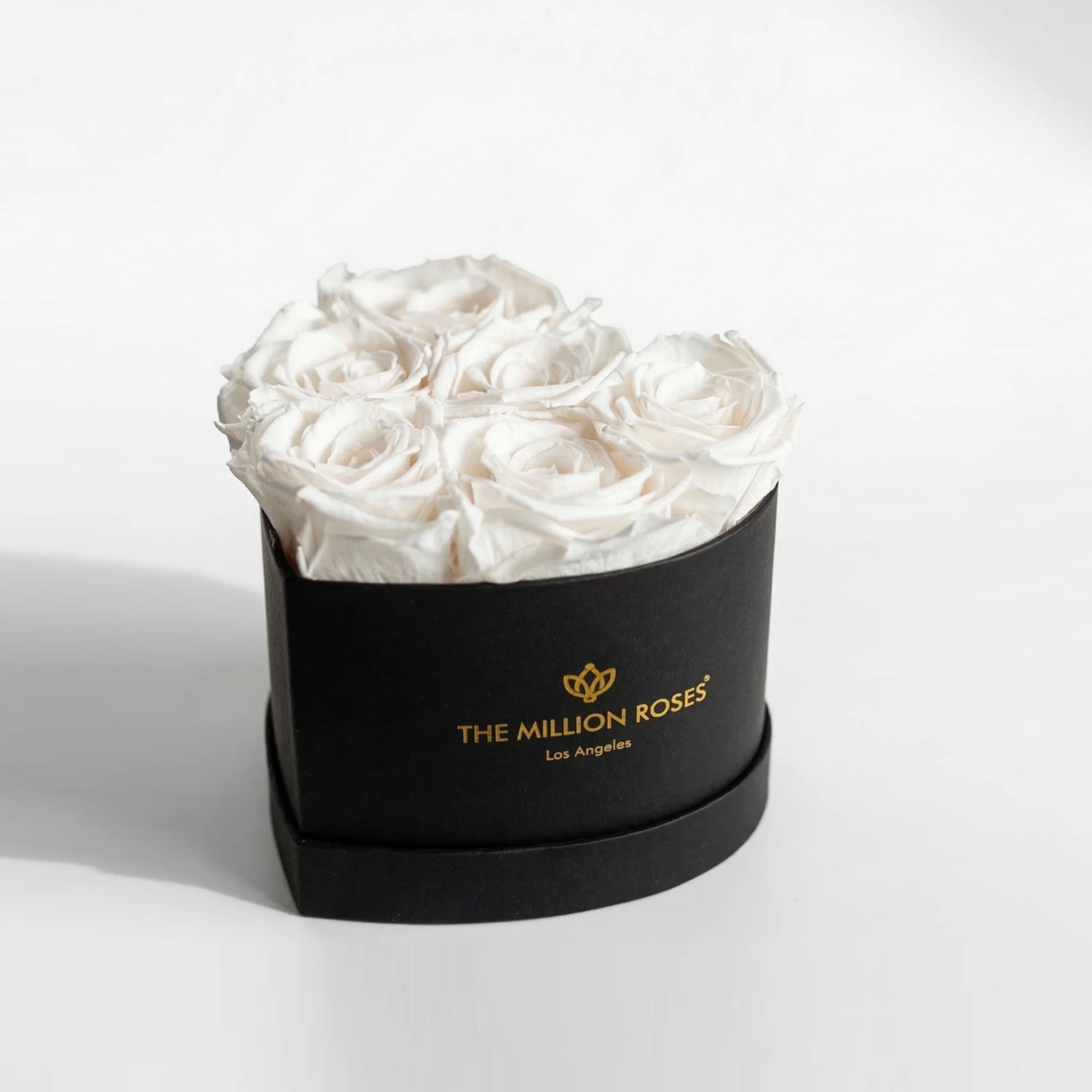 Black box holding six white roses formed into a heart shape