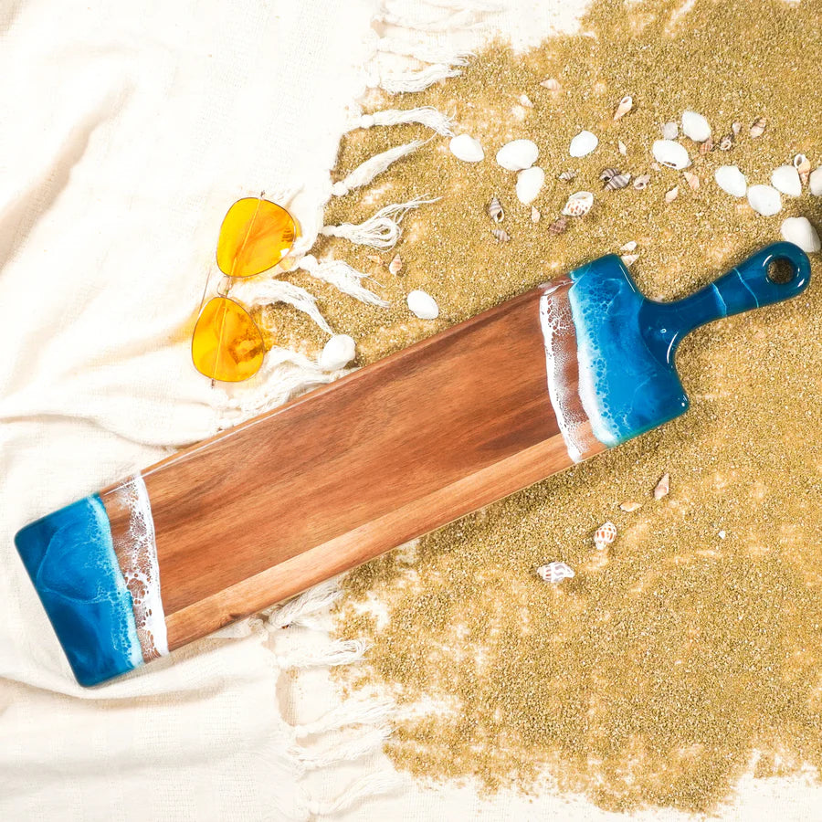 Wooden baguette resin serving tray with blue handle on a sandy background