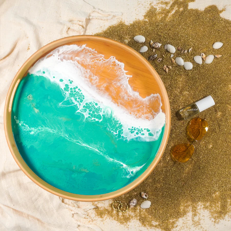 Decorative resin serving tray with ocean wave design on a sandy background