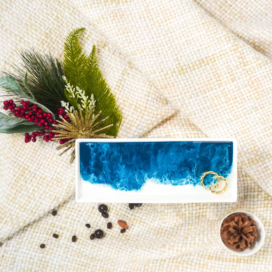 Rectangular Small Ceramic Resin Tray with gold ring on a textured beige surface with greenery and berries.