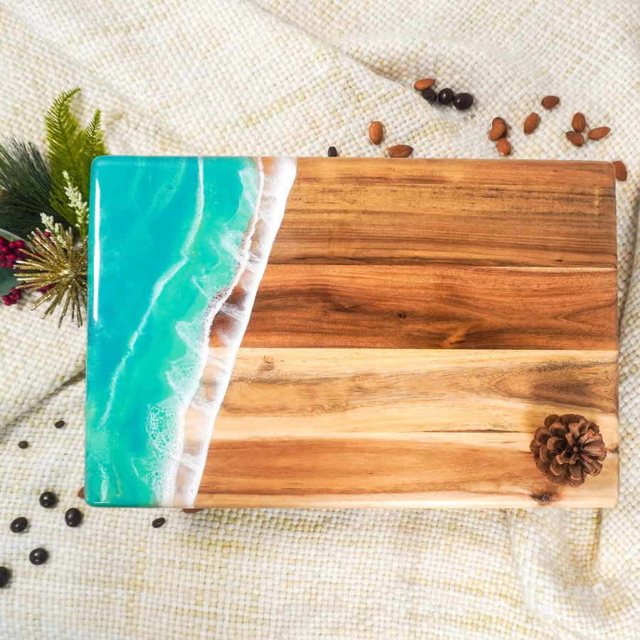 acacia resin serving bread board with a decorative edge featuring a blue ocean design on a textured surface.