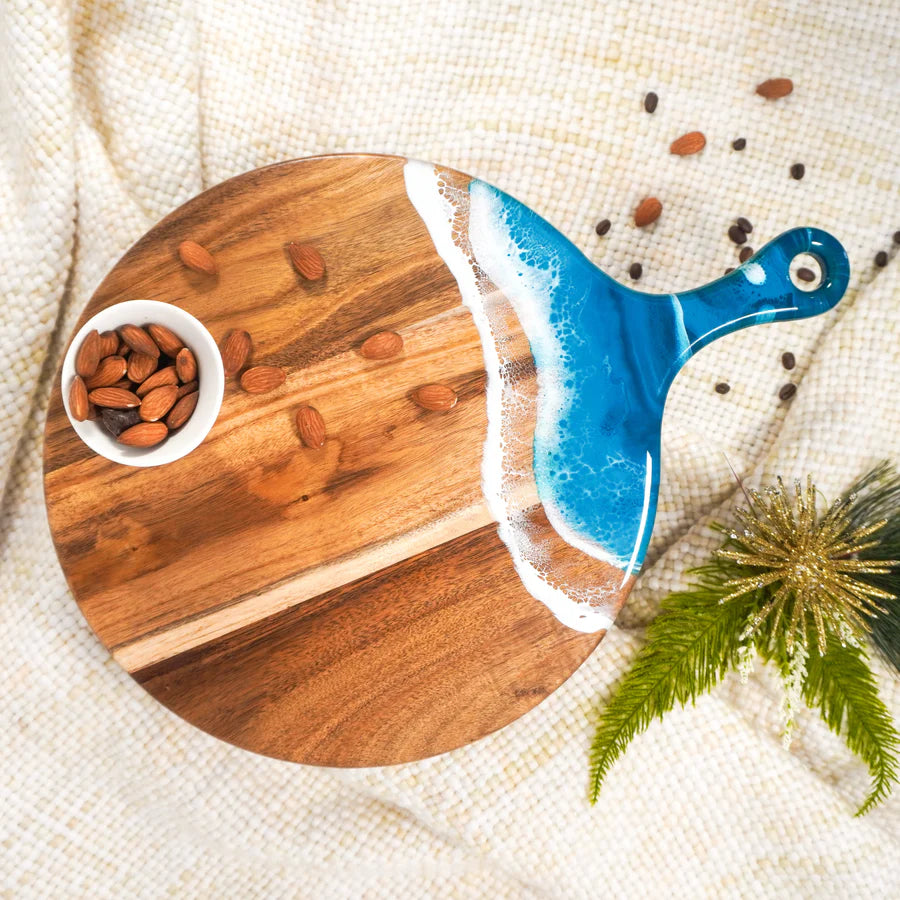 Wooden Cheese Paddle Acacia Serving Charcuterie Board with a blue handle, almonds, and a small bowl on a textured surface.