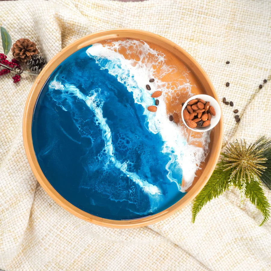Decorative resin serving tray with blue ocean design and wooden rim on a textured surface.