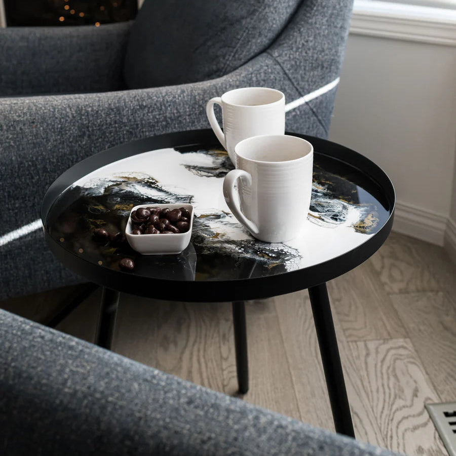 Gray armchair with a small resin round table holding two white mugs and a small bowl in a cozy room.