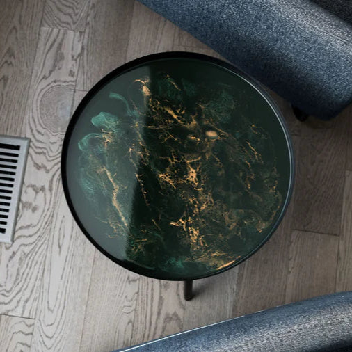 Round glass resin table with a marble design on a wooden floor.