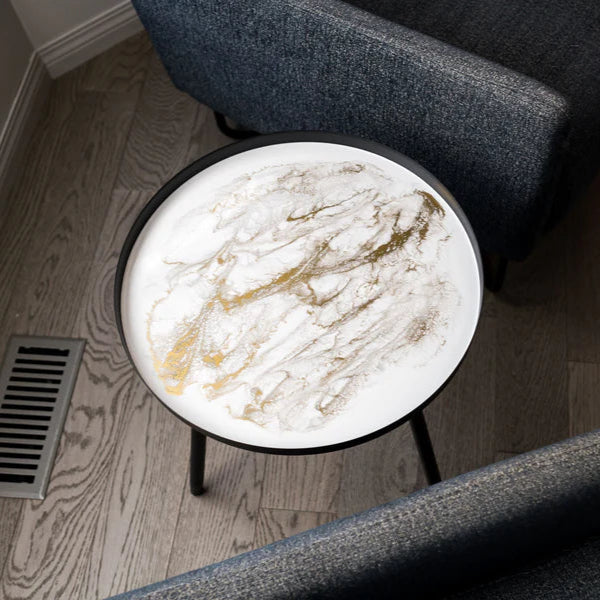 Round resin marble coffee table in a living room setting with gray chairs.