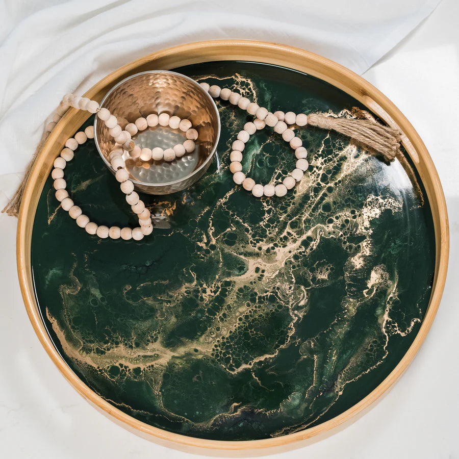 Round resin serving tray with decorative items on a white surface