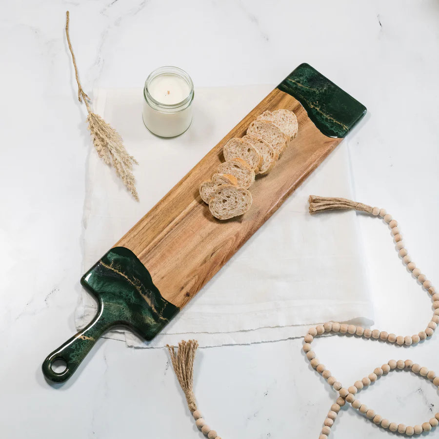 Wooden baguette resin serving tray with green edges, bread slices, and a candle on a light background