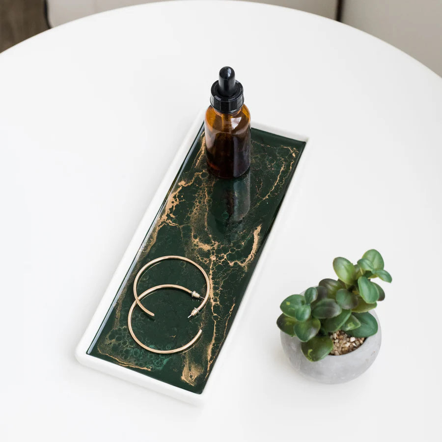 Green marble Small Ceramic Resin Tray with a bottle, earrings, and small plant on a white surface