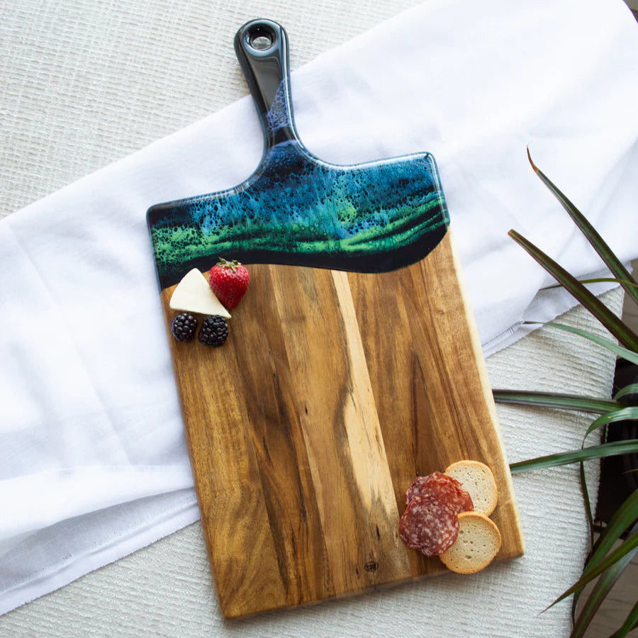 Wooden resin charcuterie board with a decorative handle on a light surface.