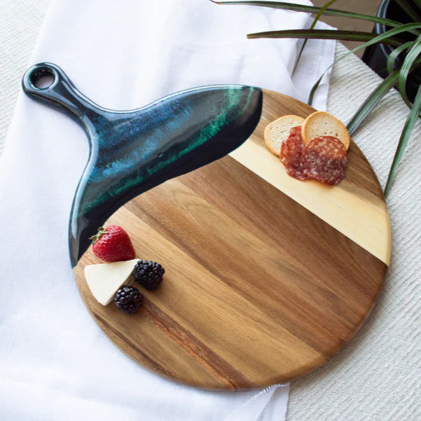 Wooden Cheese Paddle Acacia Serving Charcuterie Board with a black handle, cheese, and fruits on a white surface.