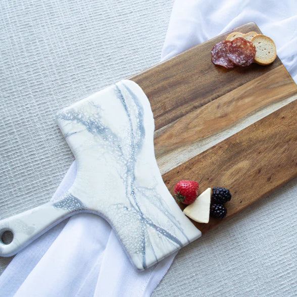 Wooden resin charcuterie board with marble handle and fruit on a light surface