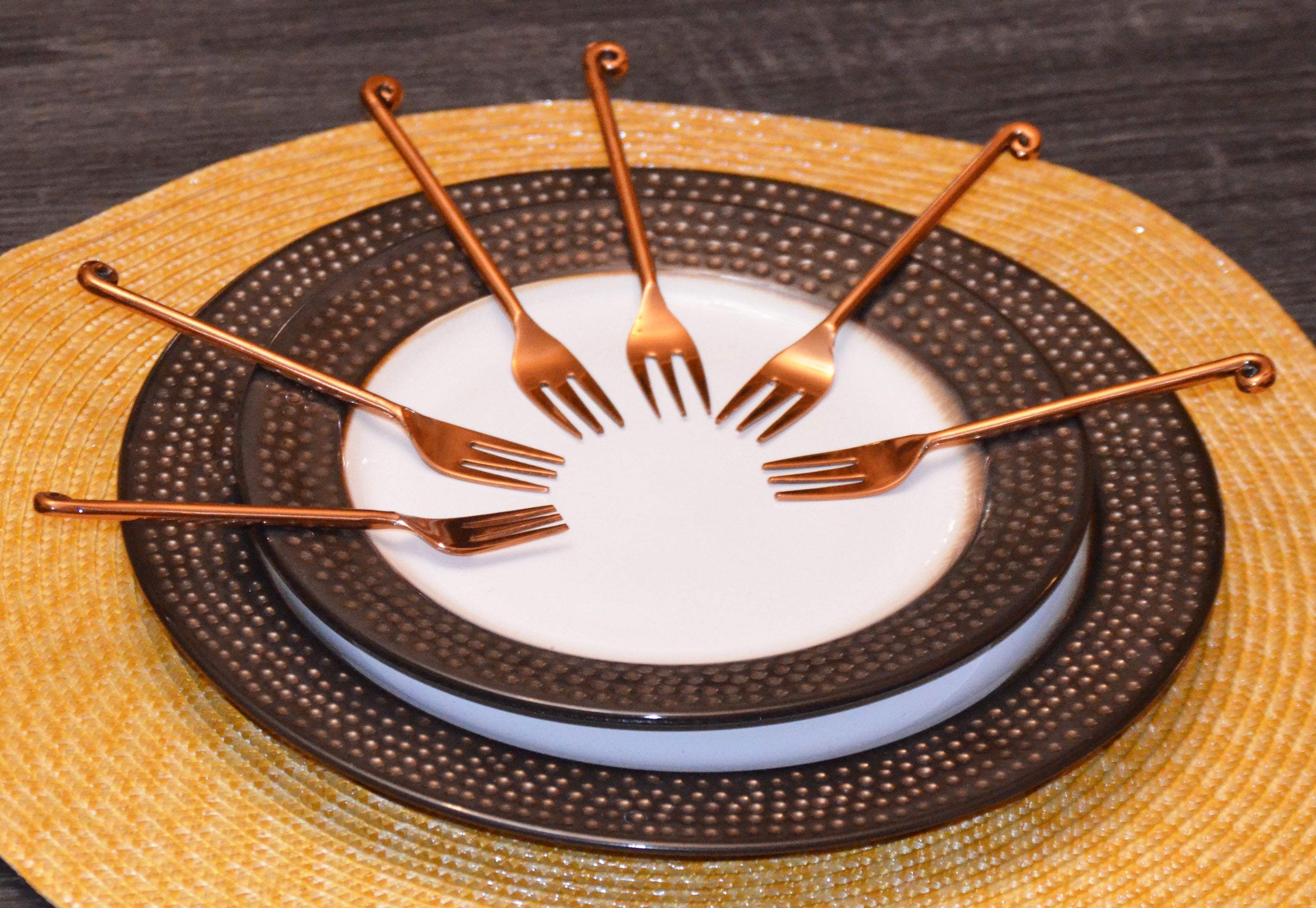 Set of six Vibhsa copper finish appetizer forks arranged on fabric with dark rose gold polish
