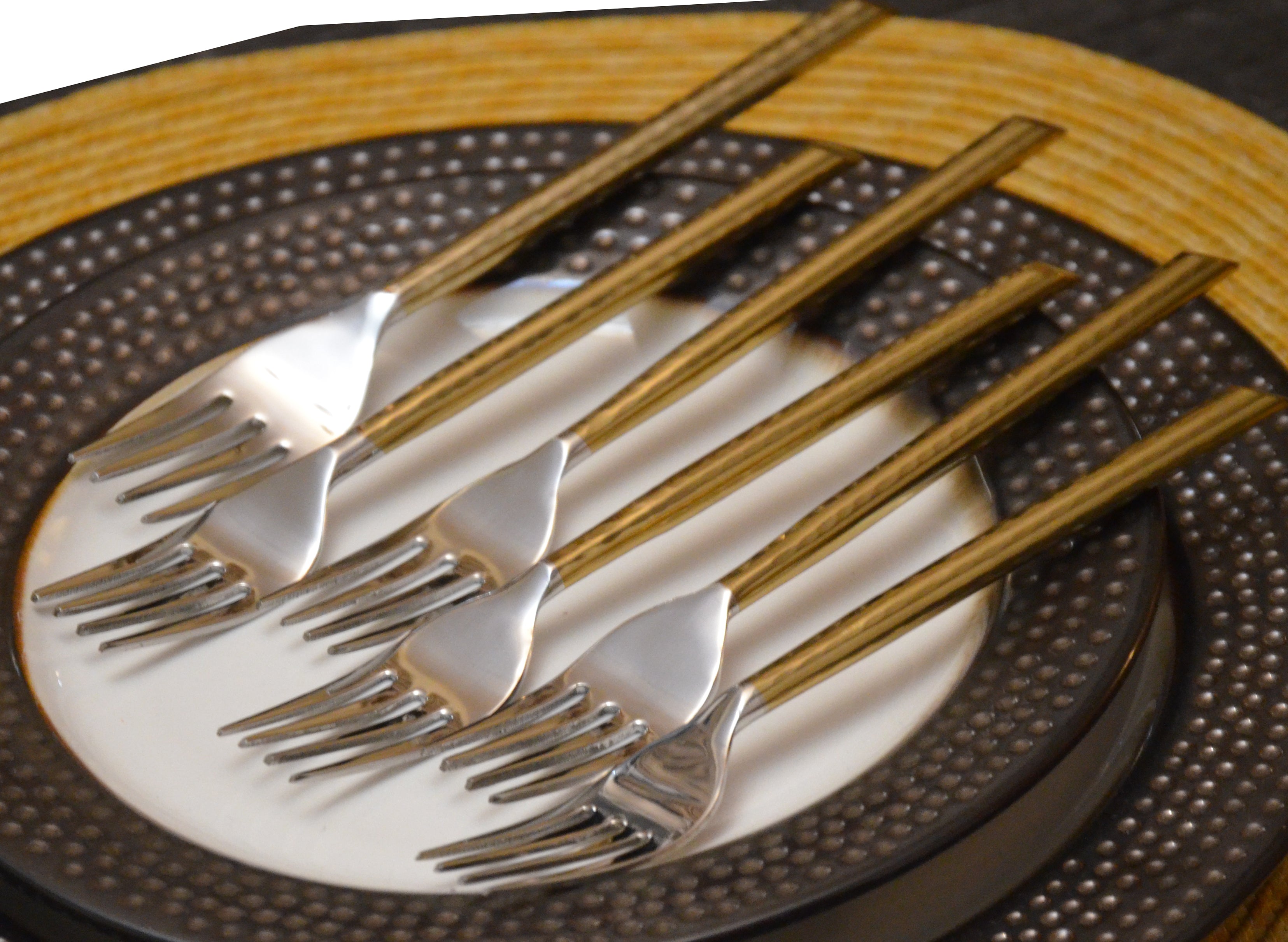 Set of six golden stainless steel dinner forks with hammered handles displayed on a neutral surface