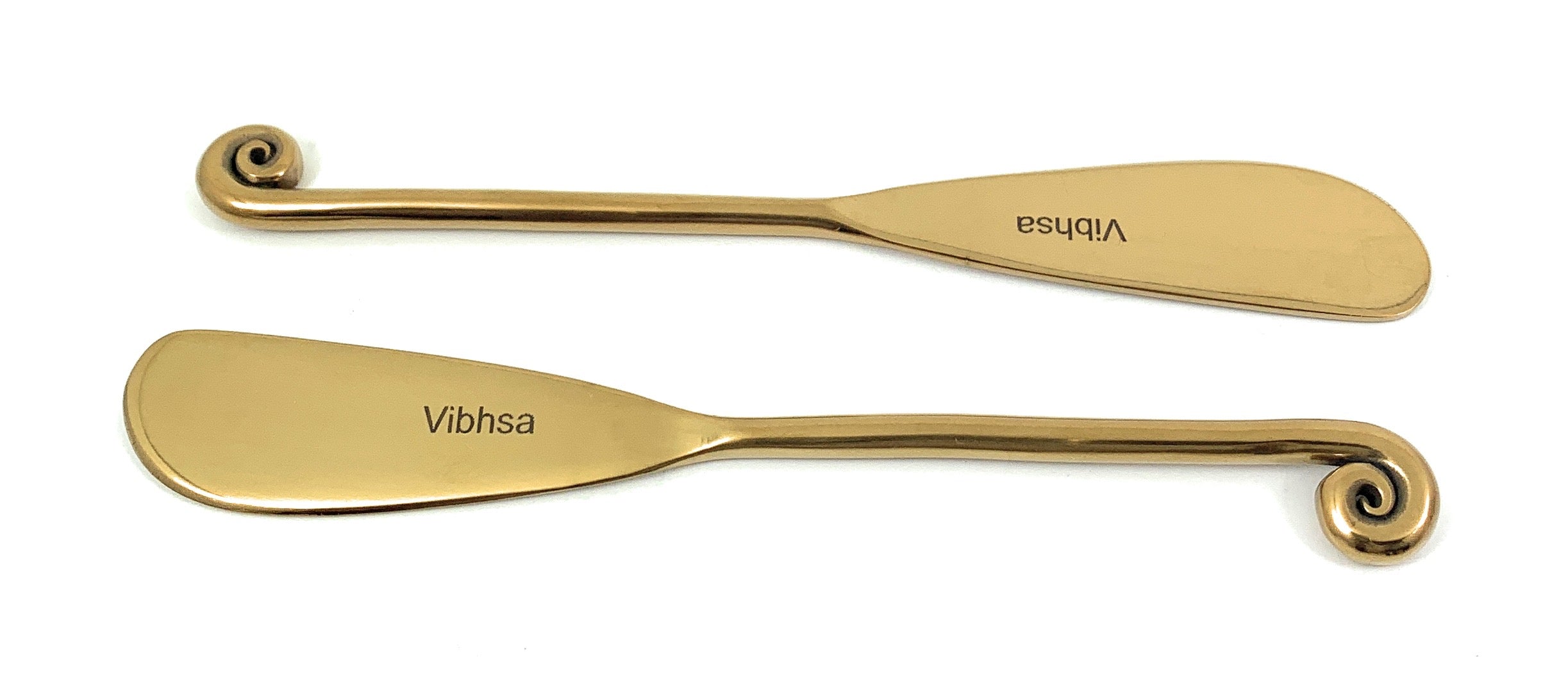 Set of six golden butter spreader knives with glossy copper finish arranged on white surface