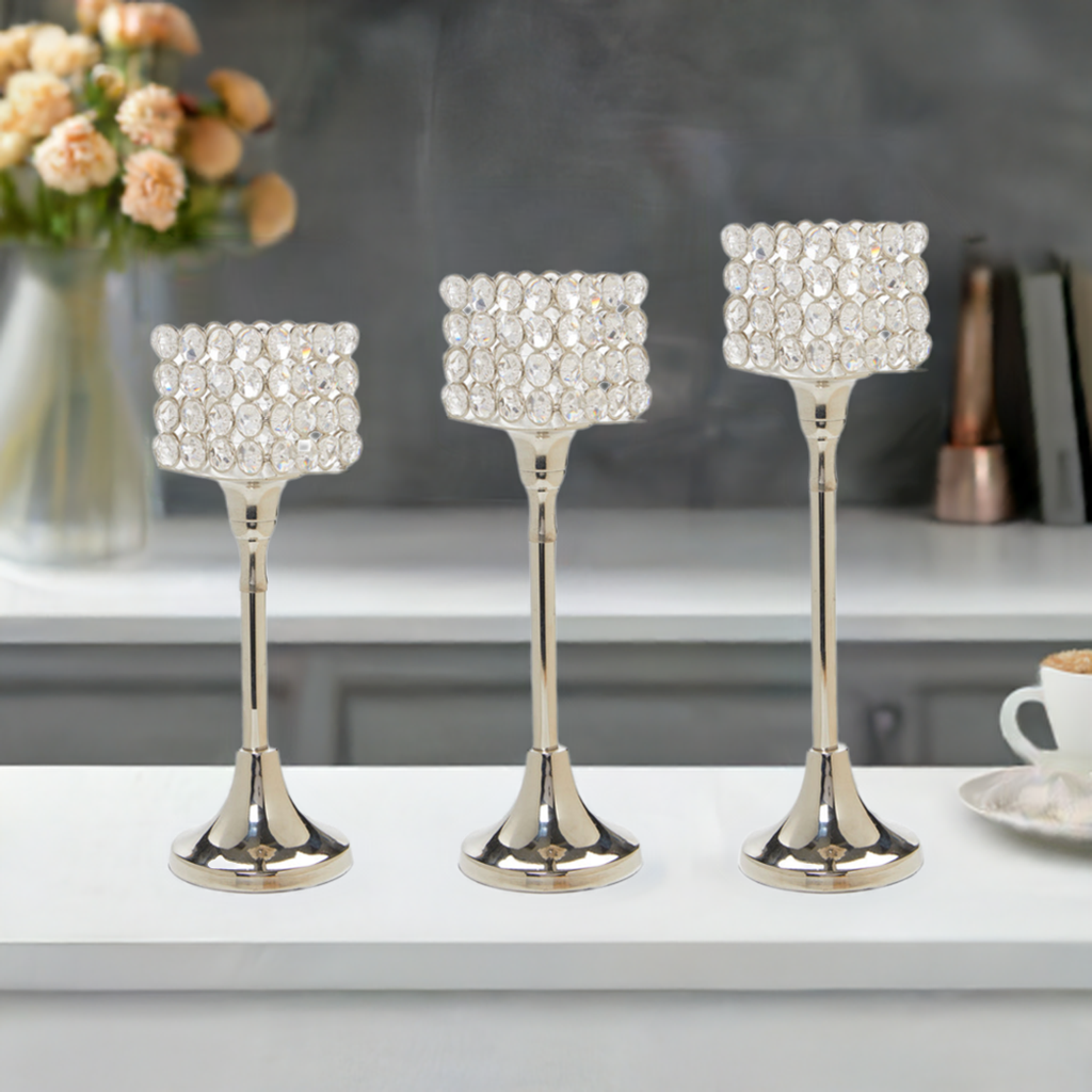 Set of three Vibhsa crystal aluminium candle holders with silver nickel finish on a table