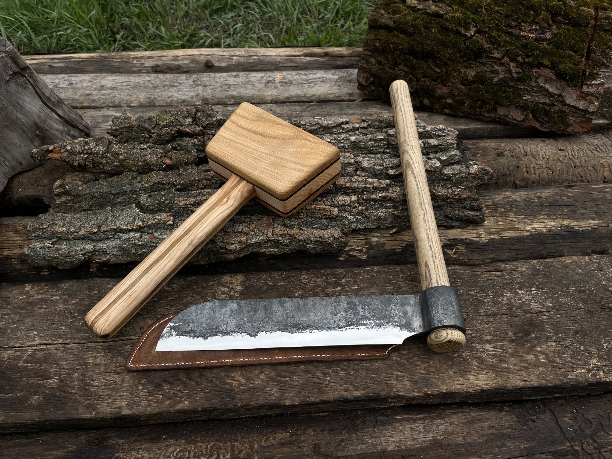 Hand-forged splitting froe with wooden mallet on wooden surface