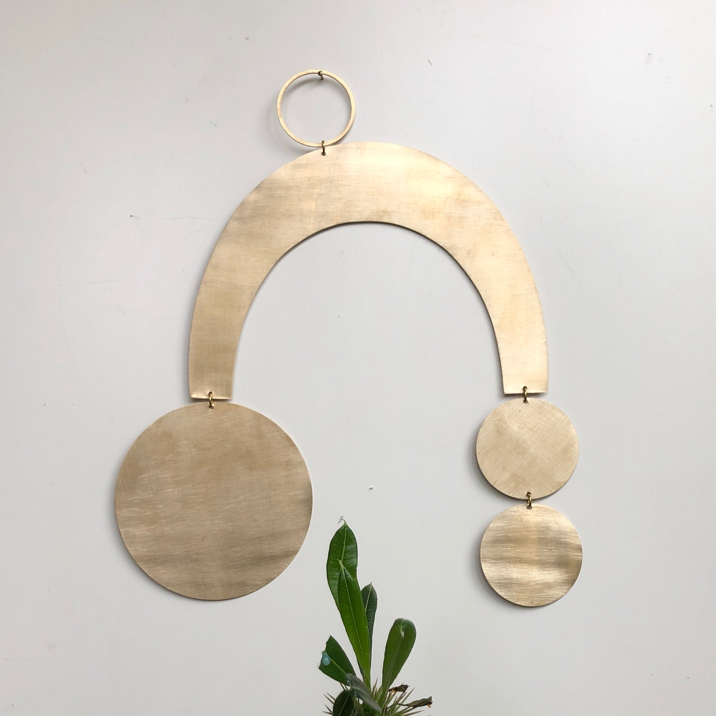 Sun Halo brass wall hanging by Vida + Luz, hand-cut and brushed, shown on neutral wall