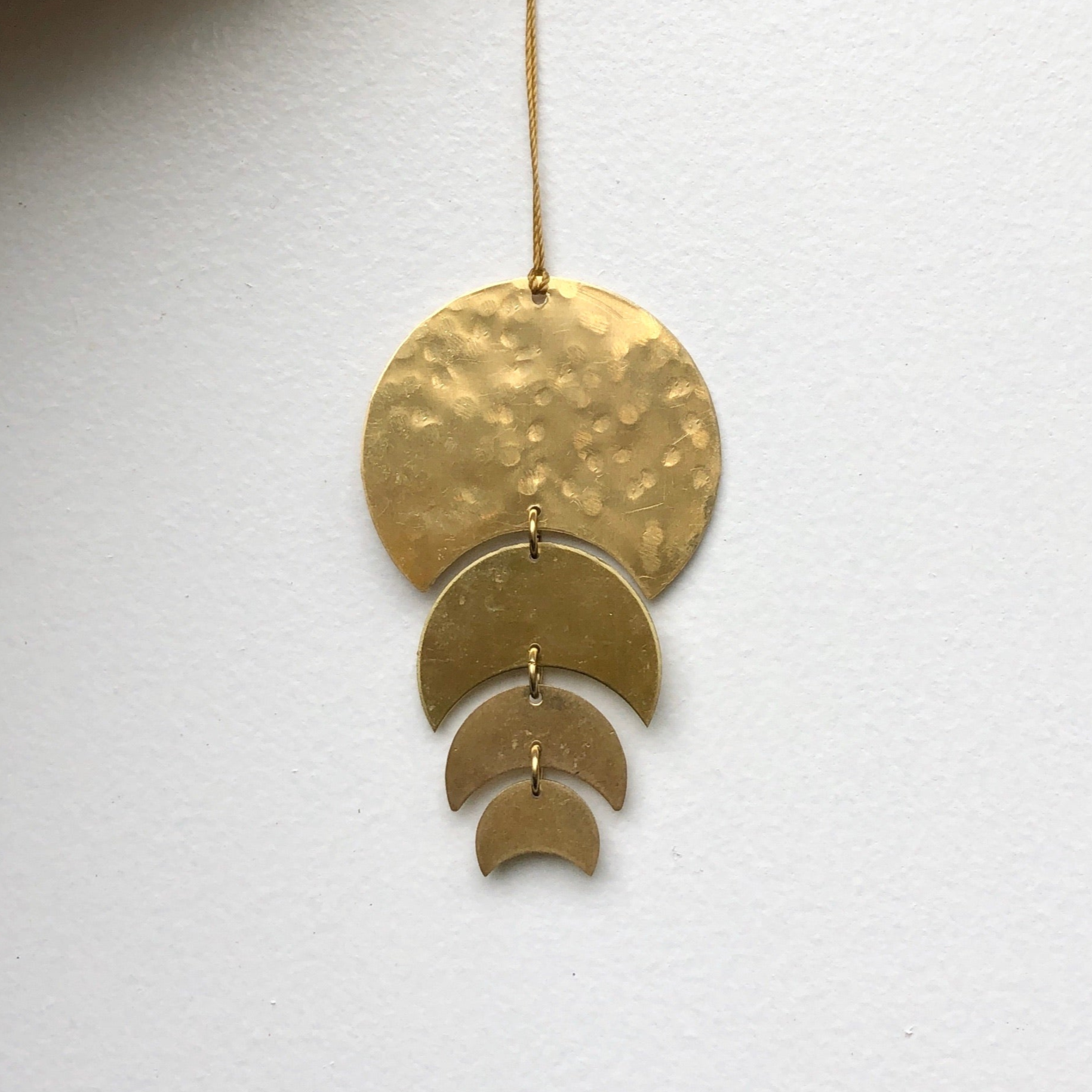 Just a Phase Ornament hanging, showing its thin brass phases with a hanging cord