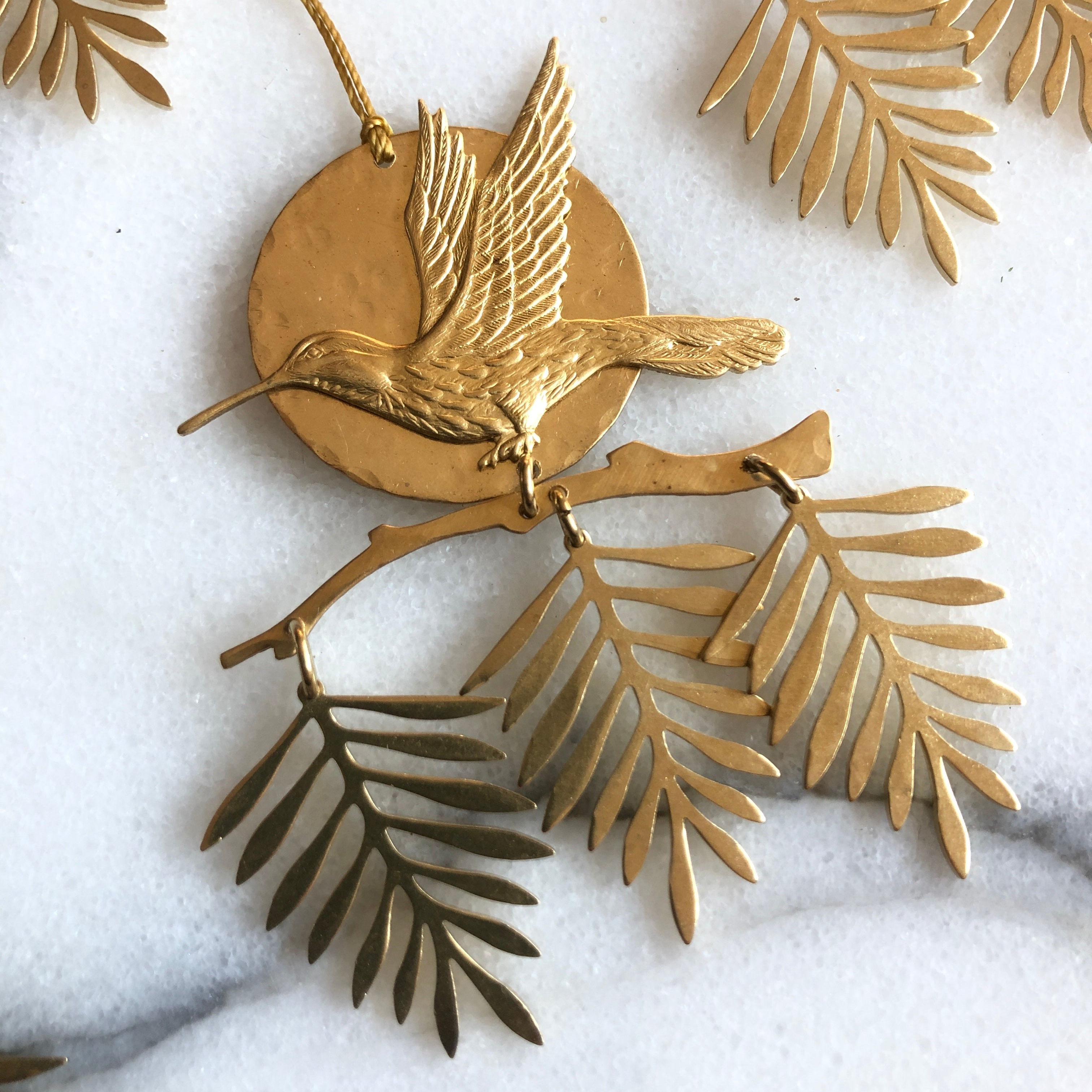 Sol Rising Mini Hanging/Ornament, hand-cut hammered brass wall hanging with hanging cord, shown indoors
