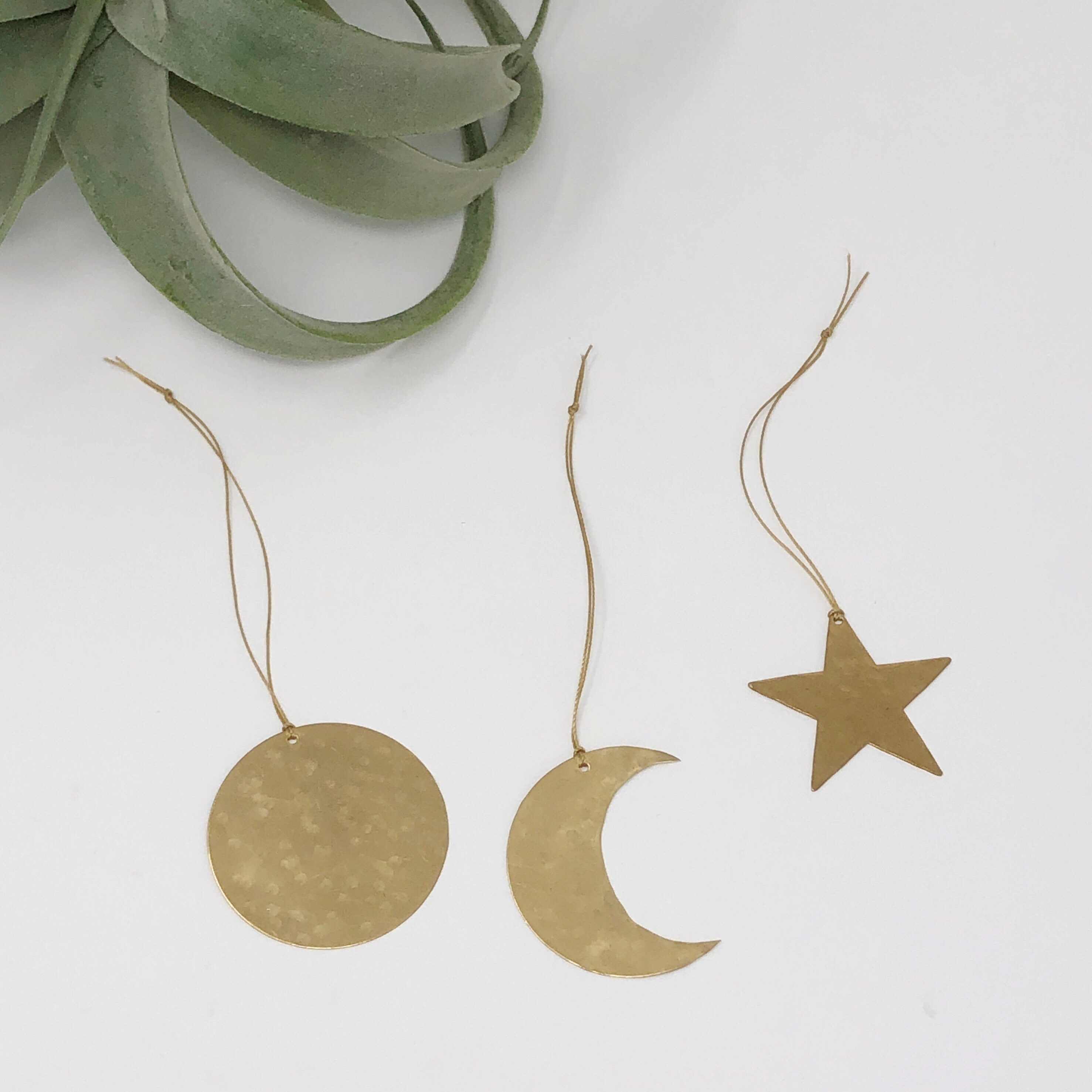 Three hand-cut hammered brass celestial shaped ornaments hanging indoors