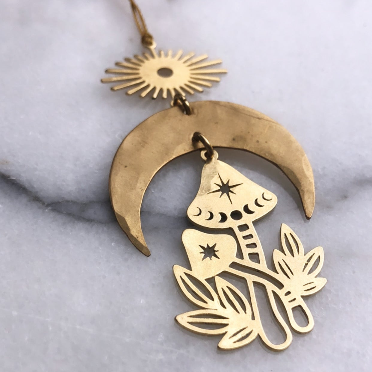 Magic Mushroom Ornament hanging against a plain wall showing its brass form