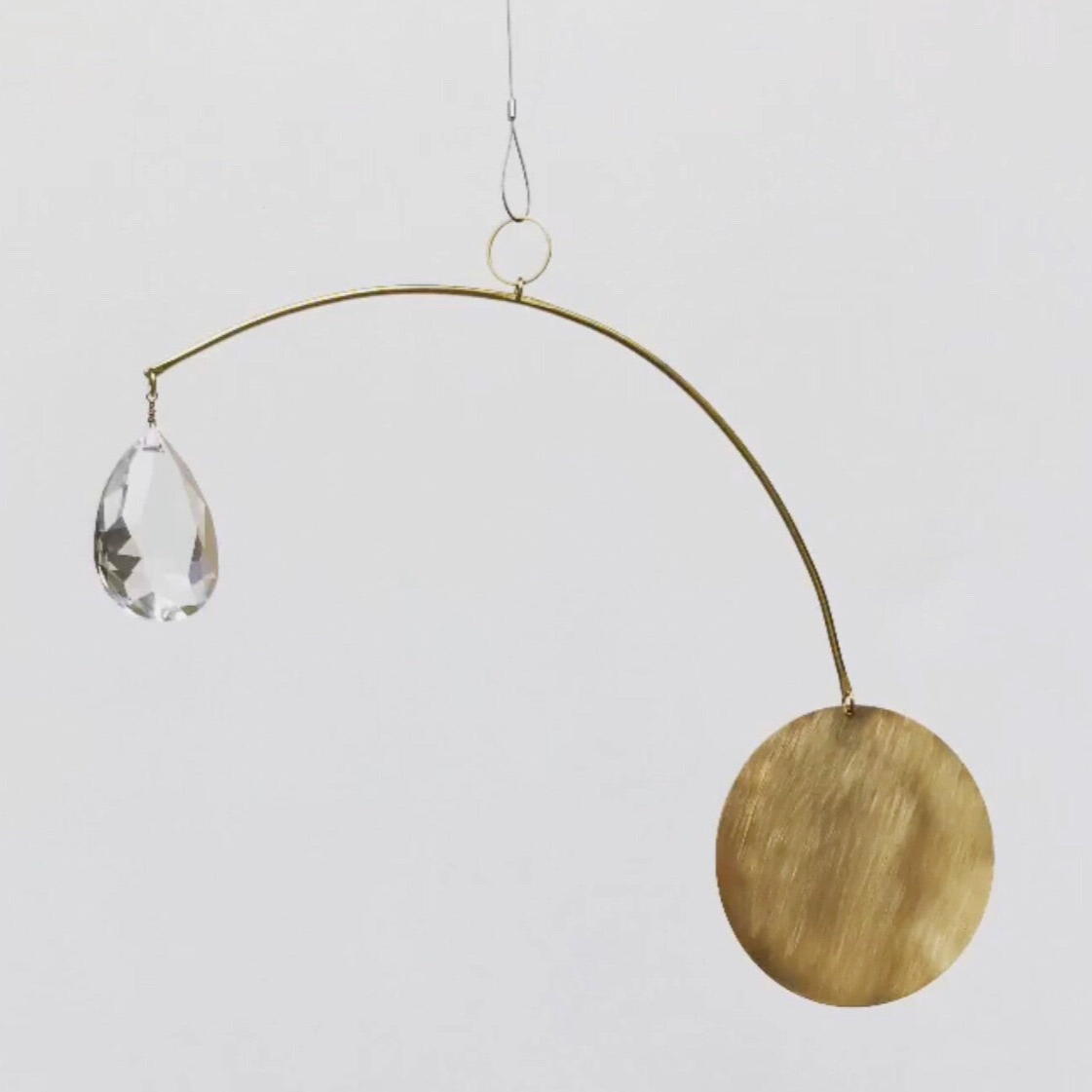 Sol Sister Suncatcher by Vida + Luz shown hanging on neutral wall, featuring brass frame and intricate vintage glass crystals.
