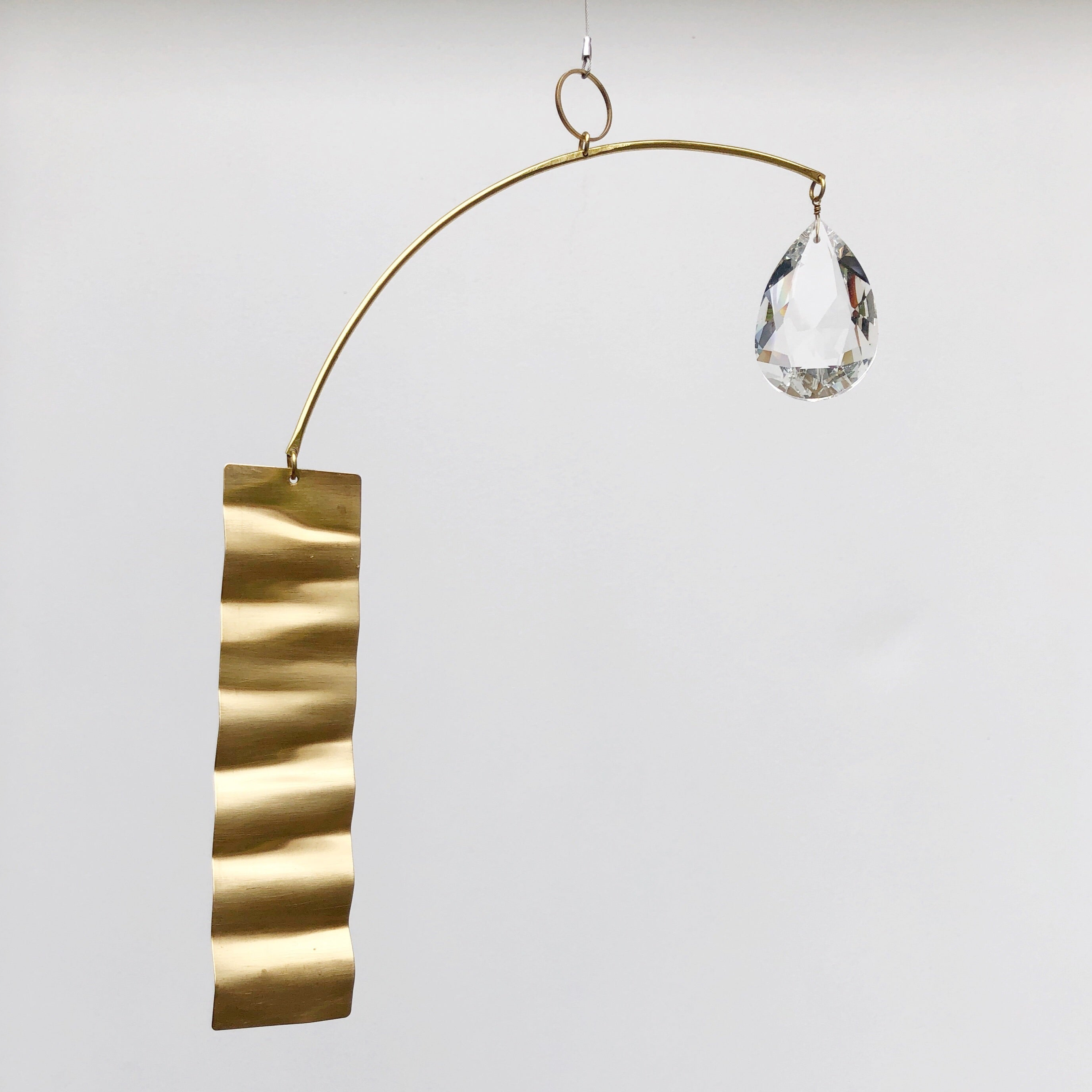 Daydream Suncatcher by Vida + Luz showing brass sheet with glass crystal accents hanging indoors