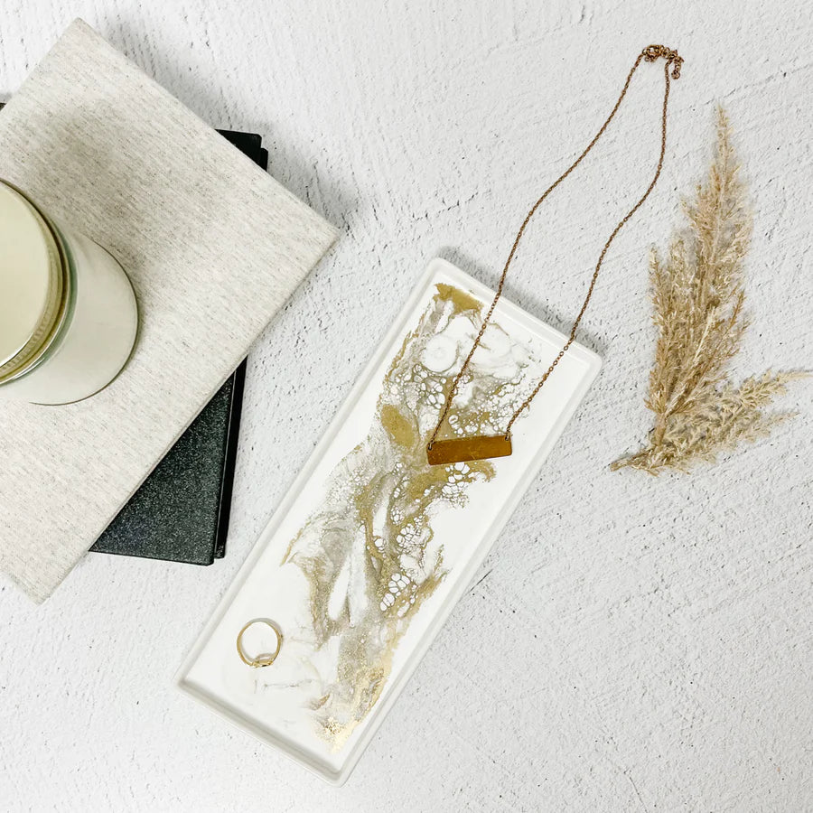 Necklace on a white rectangular Small Ceramic Resin Tray with gold accents, placed on a textured white surface.