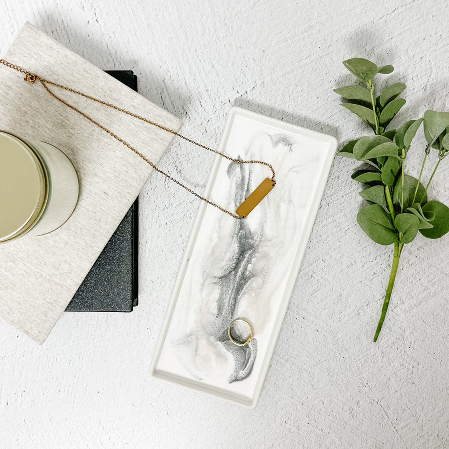 Gold necklace on a marble Small Ceramic Resin Tray with a plant and candle