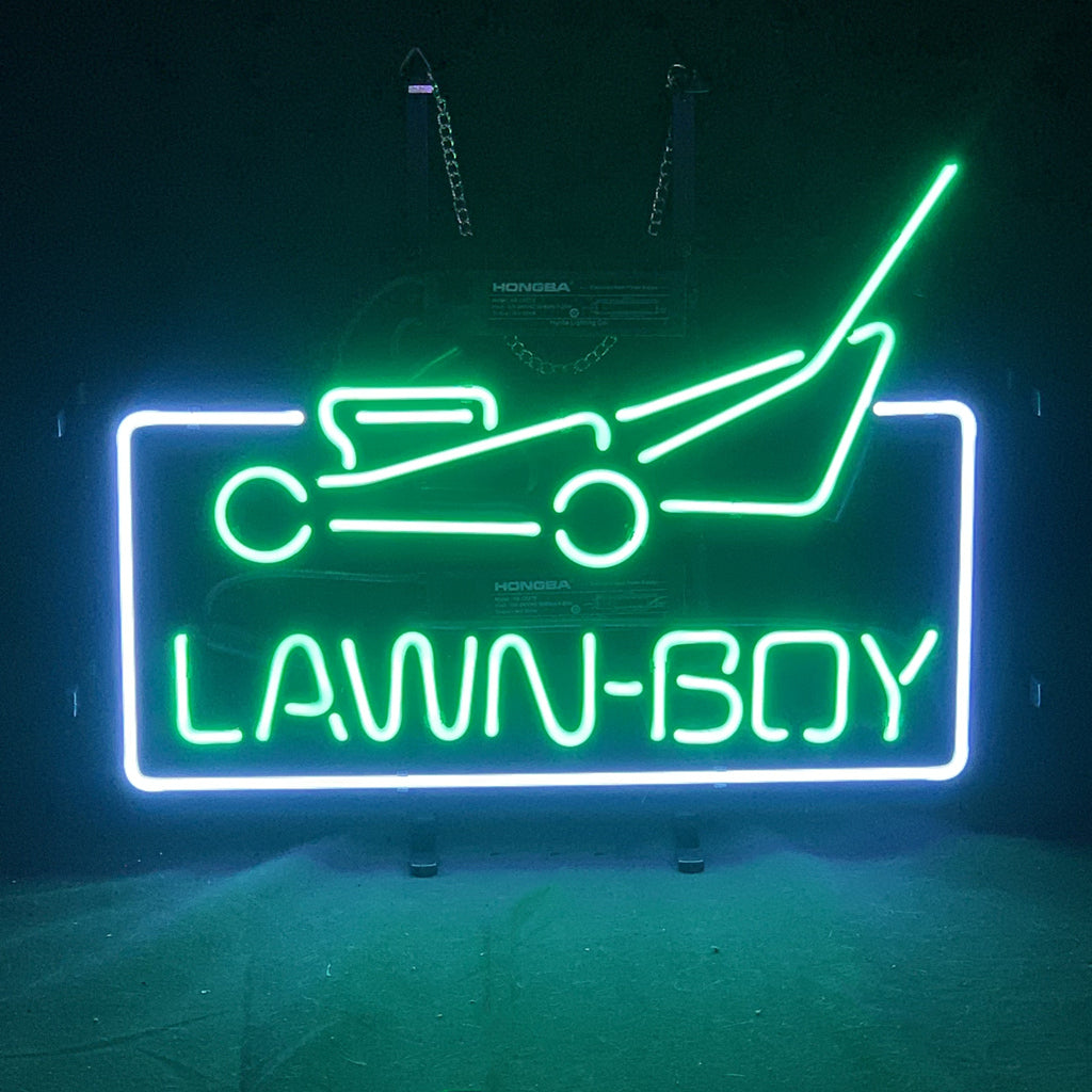 Lawn-boy Tractor shaped neon sign lit up, mounted on a metal grid backing with a hanging chain