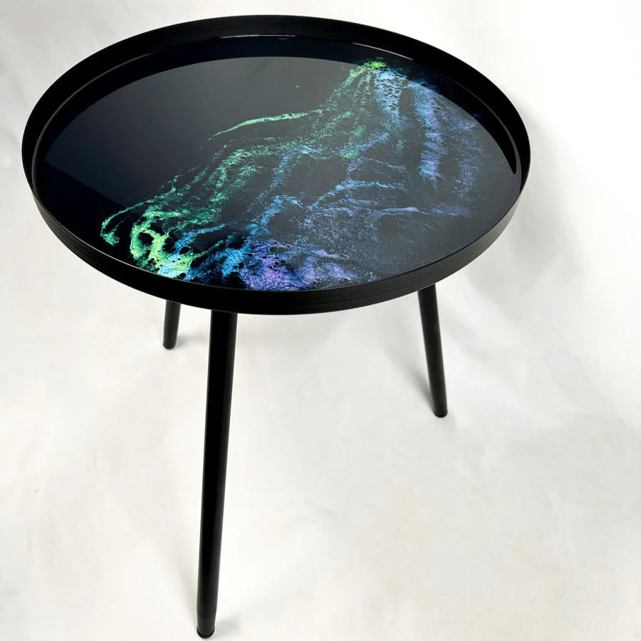 Round black resin table with a colorful abstract design on a white background