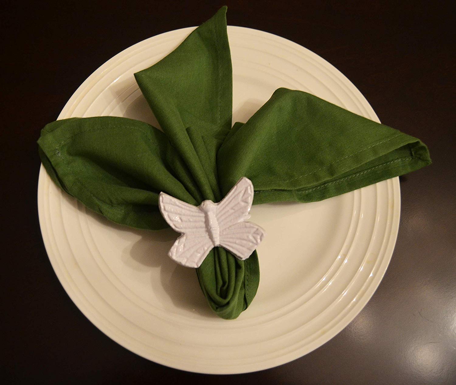 Vibhsa Butterfly White Napkin Rings Set of 4 displayed around folded white napkins on a wooden surface