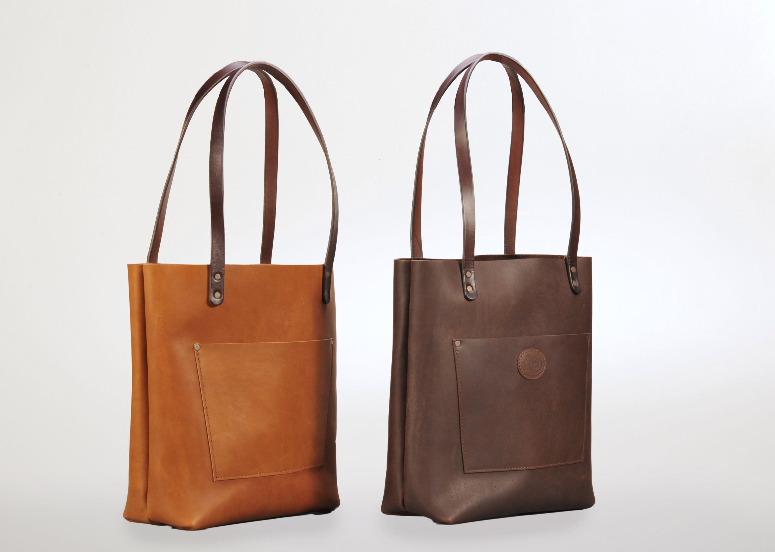 Various Enrico Bartolini leather purses and tote bags in different sizes and shades displayed on wooden background