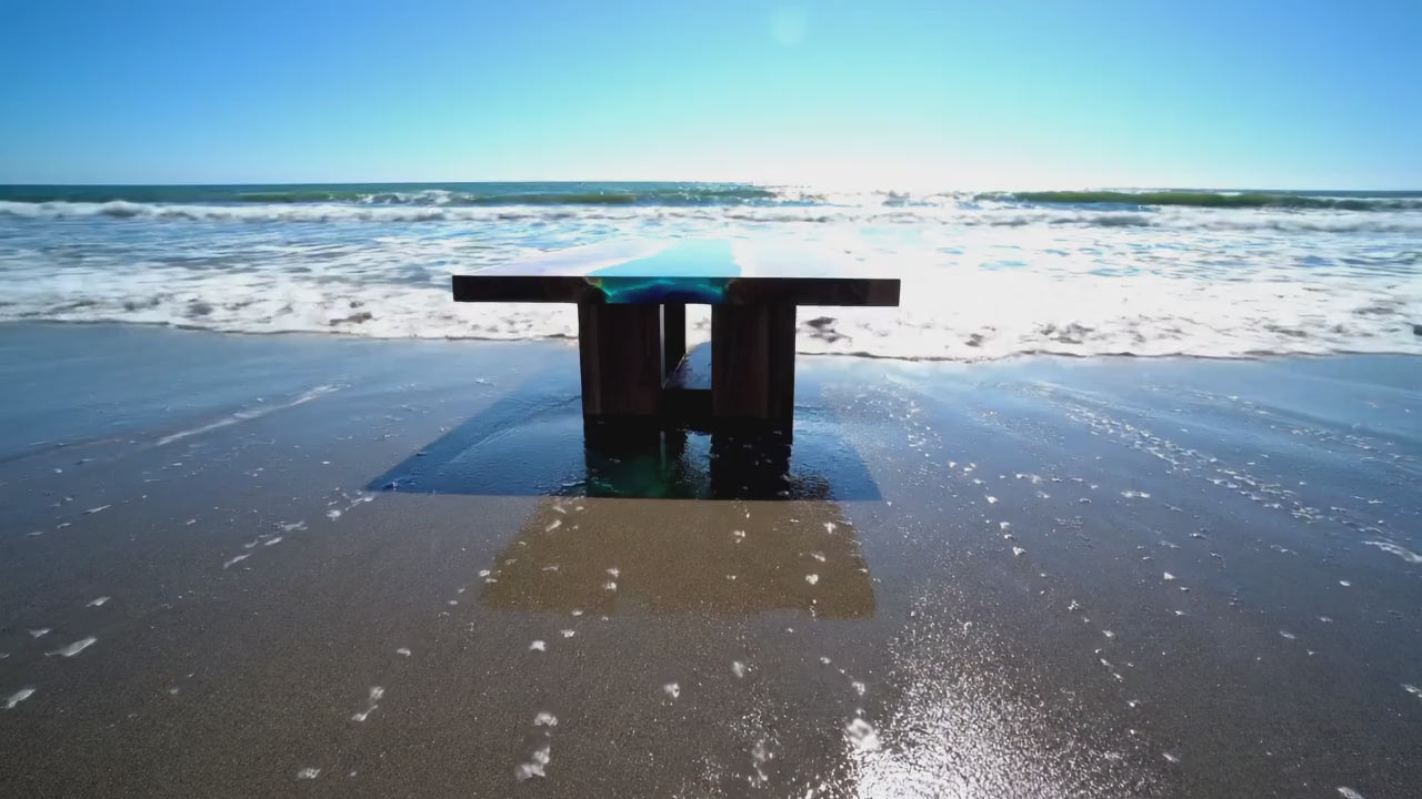 Load video: blue epoxy river ocean dining table on the beach with waves crashing into it