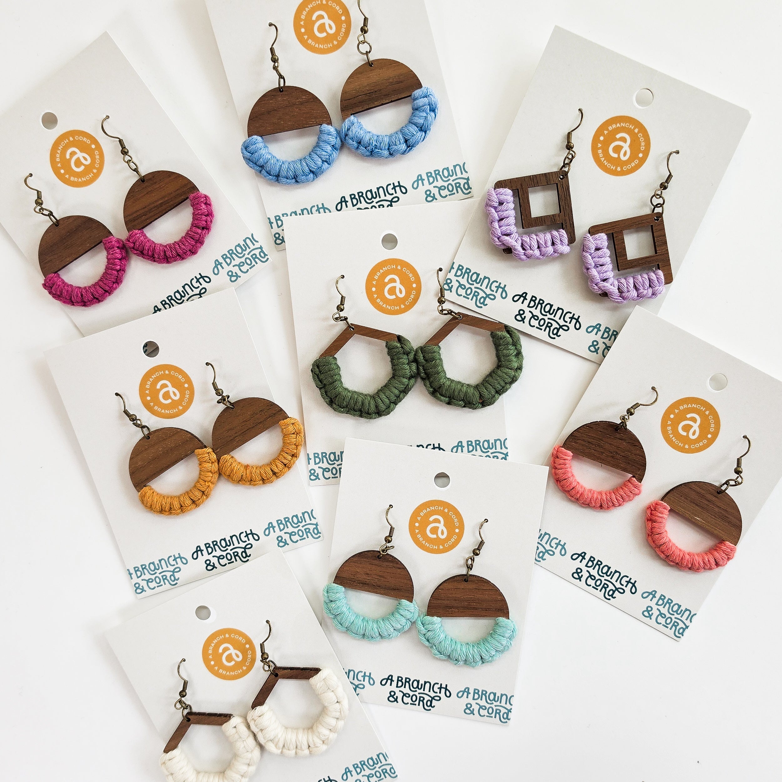 Colorful macrame knotted earrings in circle shape hanging against a neutral background