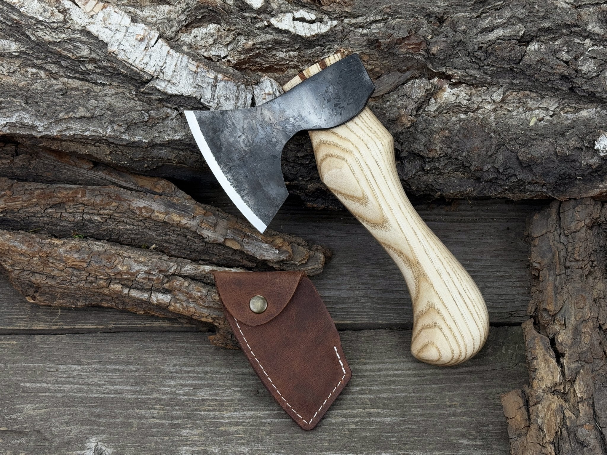 Small carving axe with carbon steel blade and ash wood handle, featuring leather sheath with belt loop