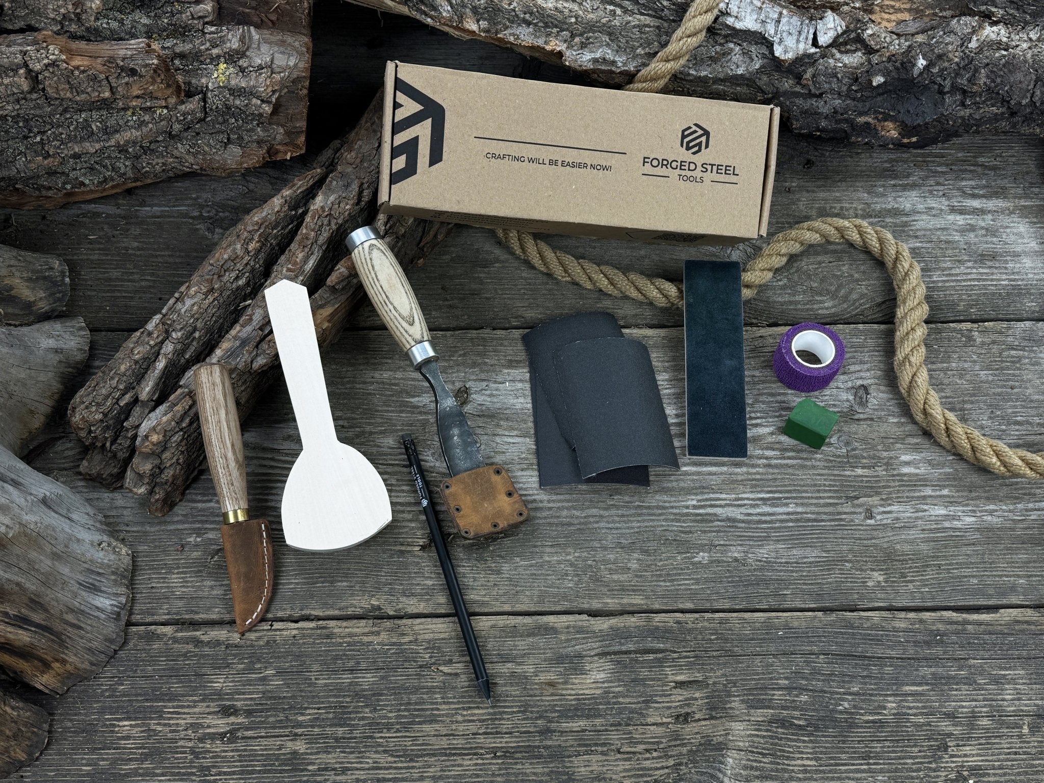 Spoon Carving Kit with bent gouge, whittling knife, wooden blank, sandpaper, sharpening board, pencil, and finger wrap