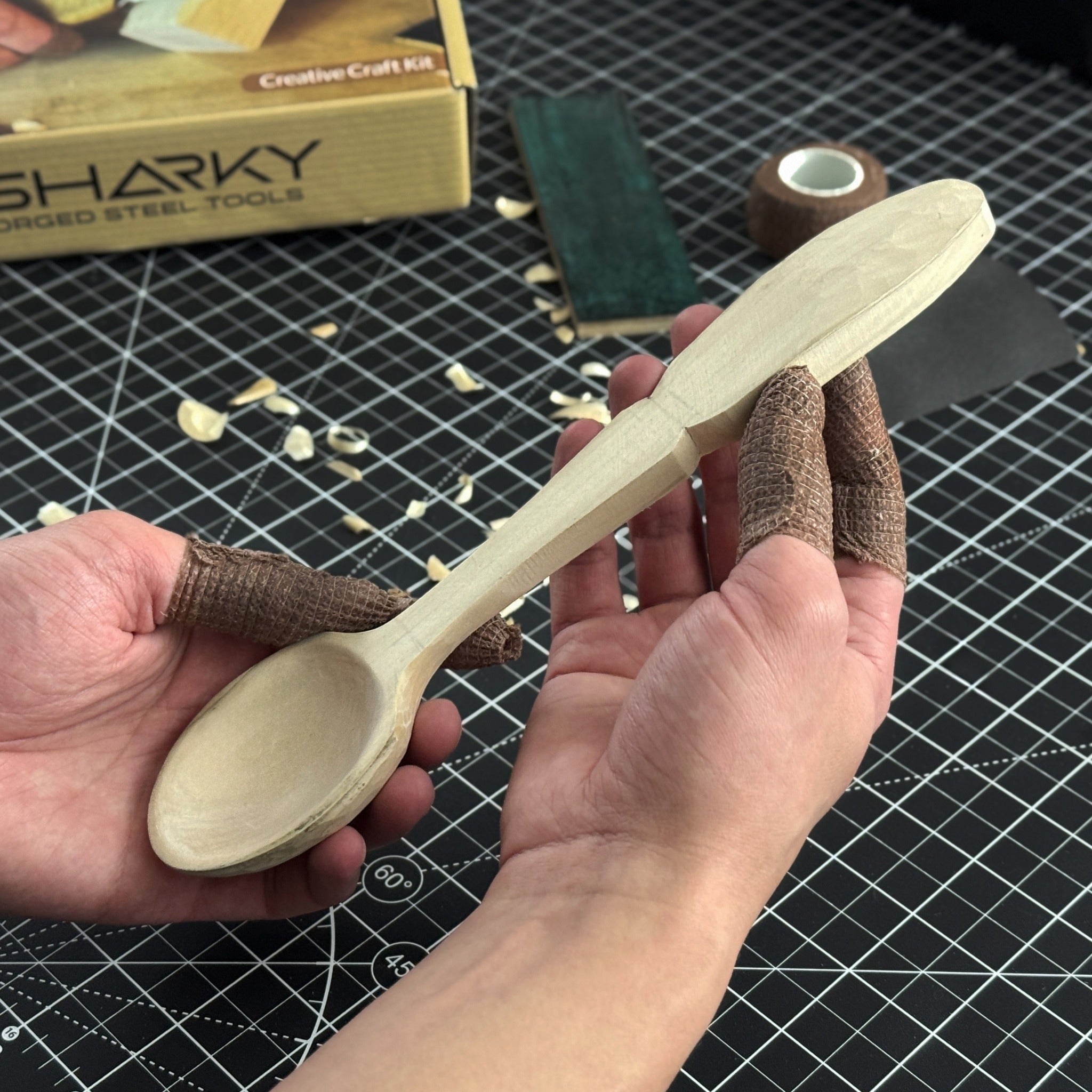 Complete Spoon Carving Kit with bent gouge, whittling knife, wooden blank, sandpaper, sharpening board, pencil, and finger wrap