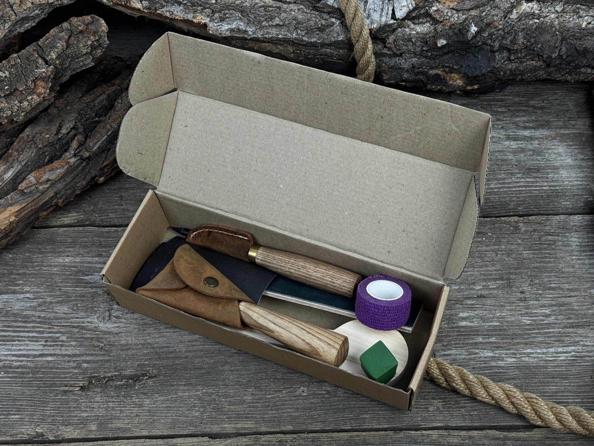 Spoon Carving Kit with knives, wooden blank, sandpaper, sharpening board, pencil, and finger wrap