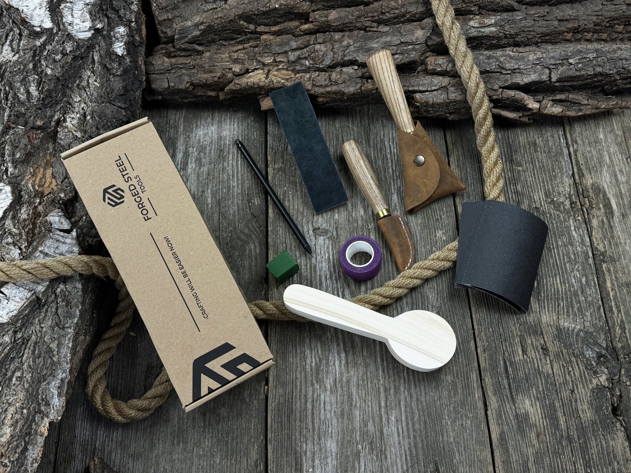 Spoon Carving Kit with knives, wooden blank, sandpaper, sharpening board, pencil, and finger wrap