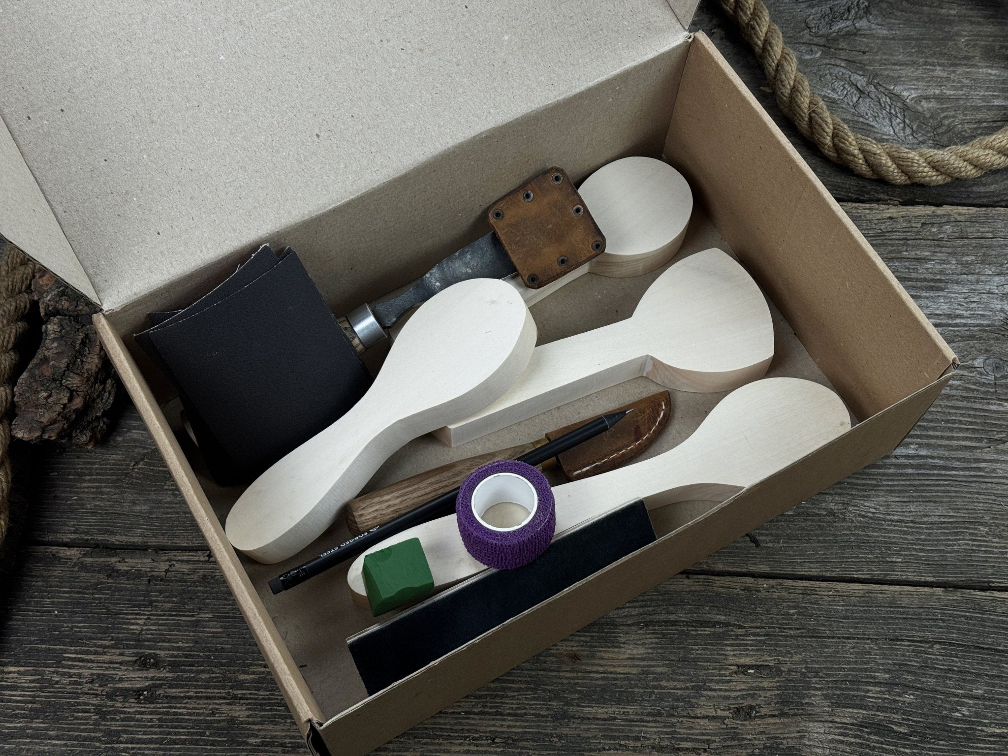 Spoon Carving Kit with hand-forged tools, wooden blanks, sandpaper, and sharpening board