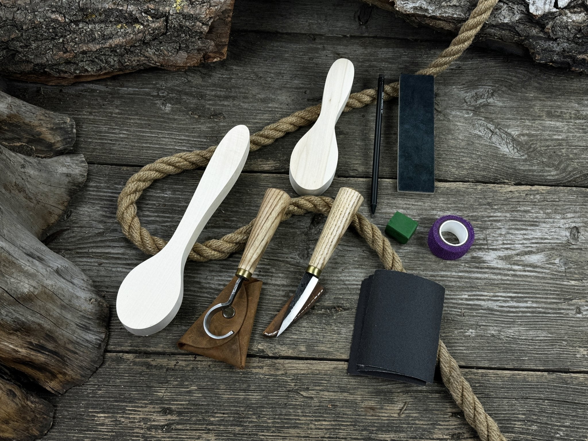 Complete spoon carving kit with knives, wooden blanks, sandpaper, sharpening board, pencil, and finger wrap