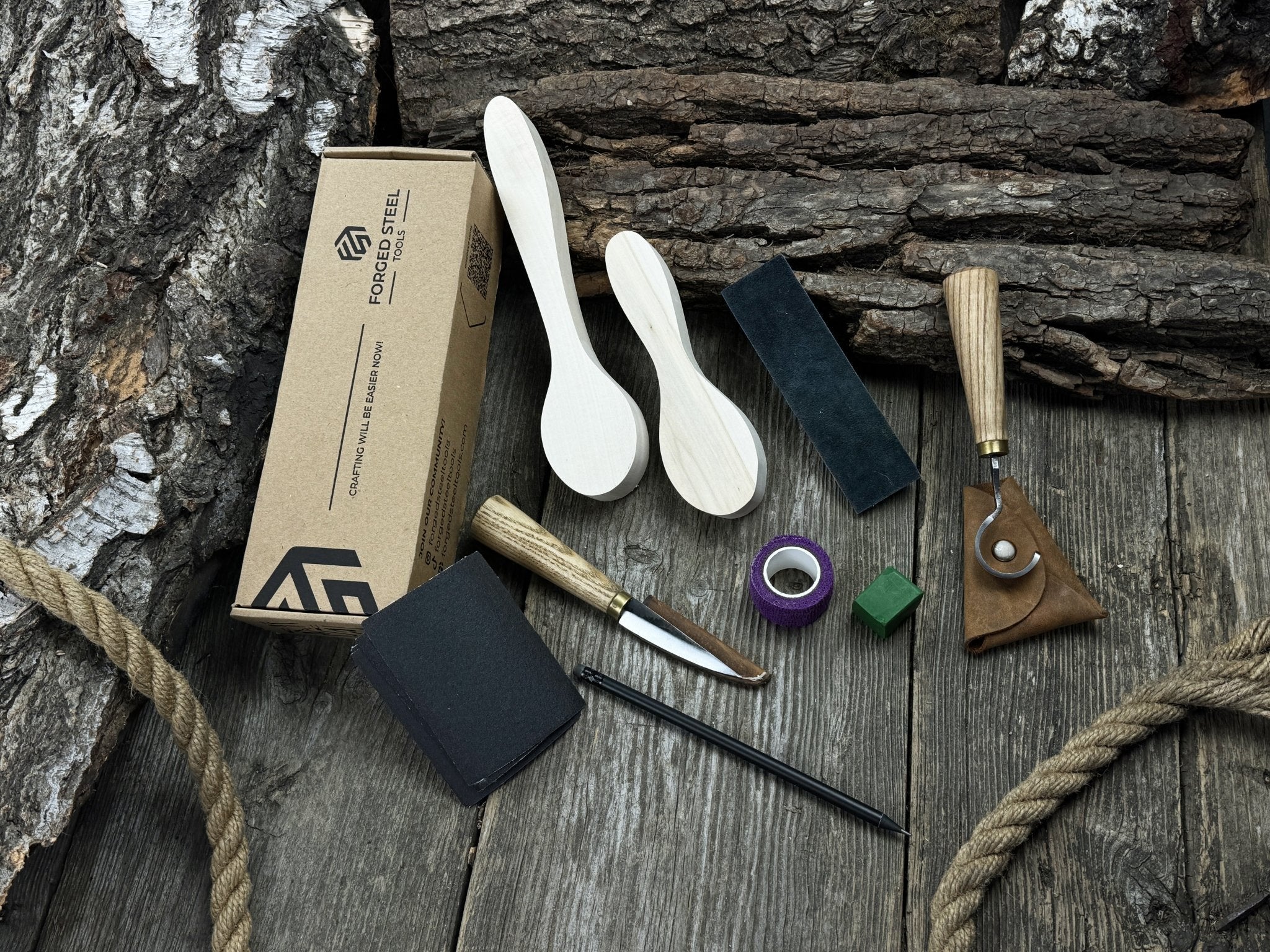 Complete spoon carving kit with knives, wooden blanks, sandpaper, sharpening board, pencil, and finger wrap
