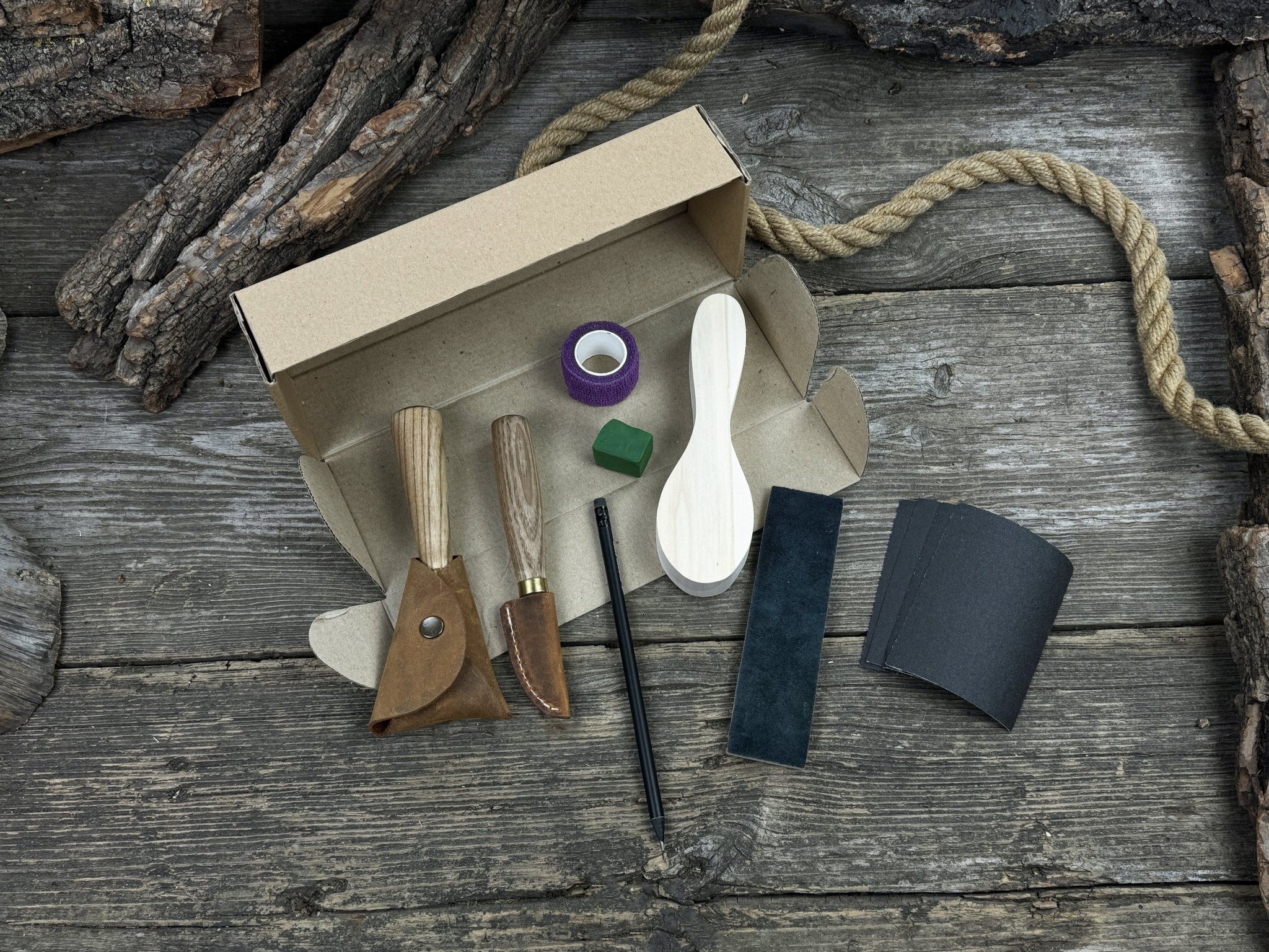 Spoon Carving Kit with knives, wooden blank, sandpaper, sharpening board, pencil, and finger wrap