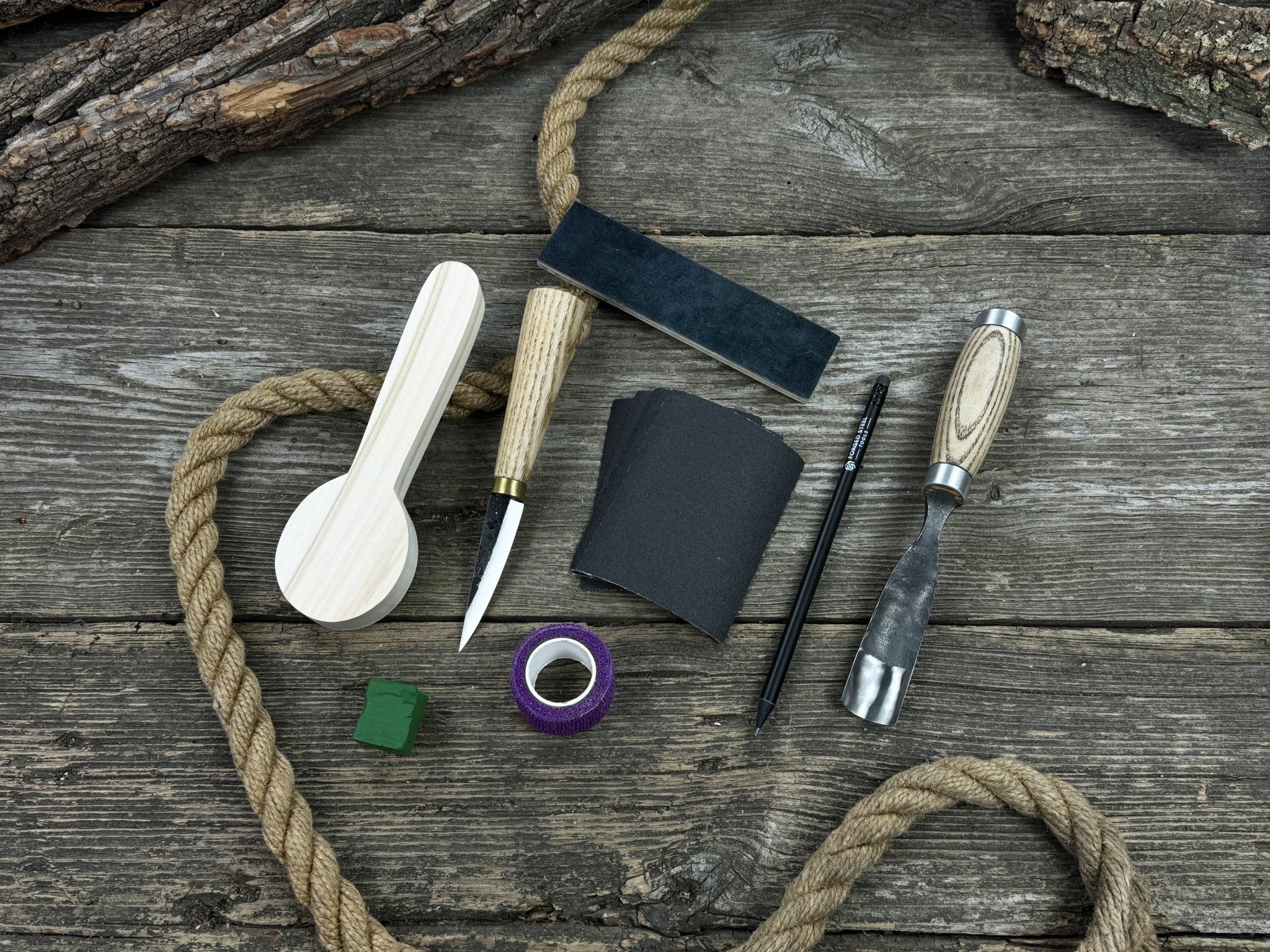 Spoon Carving Kit with knives, wooden blank, sandpaper, sharpening board, pencil, and finger wrap