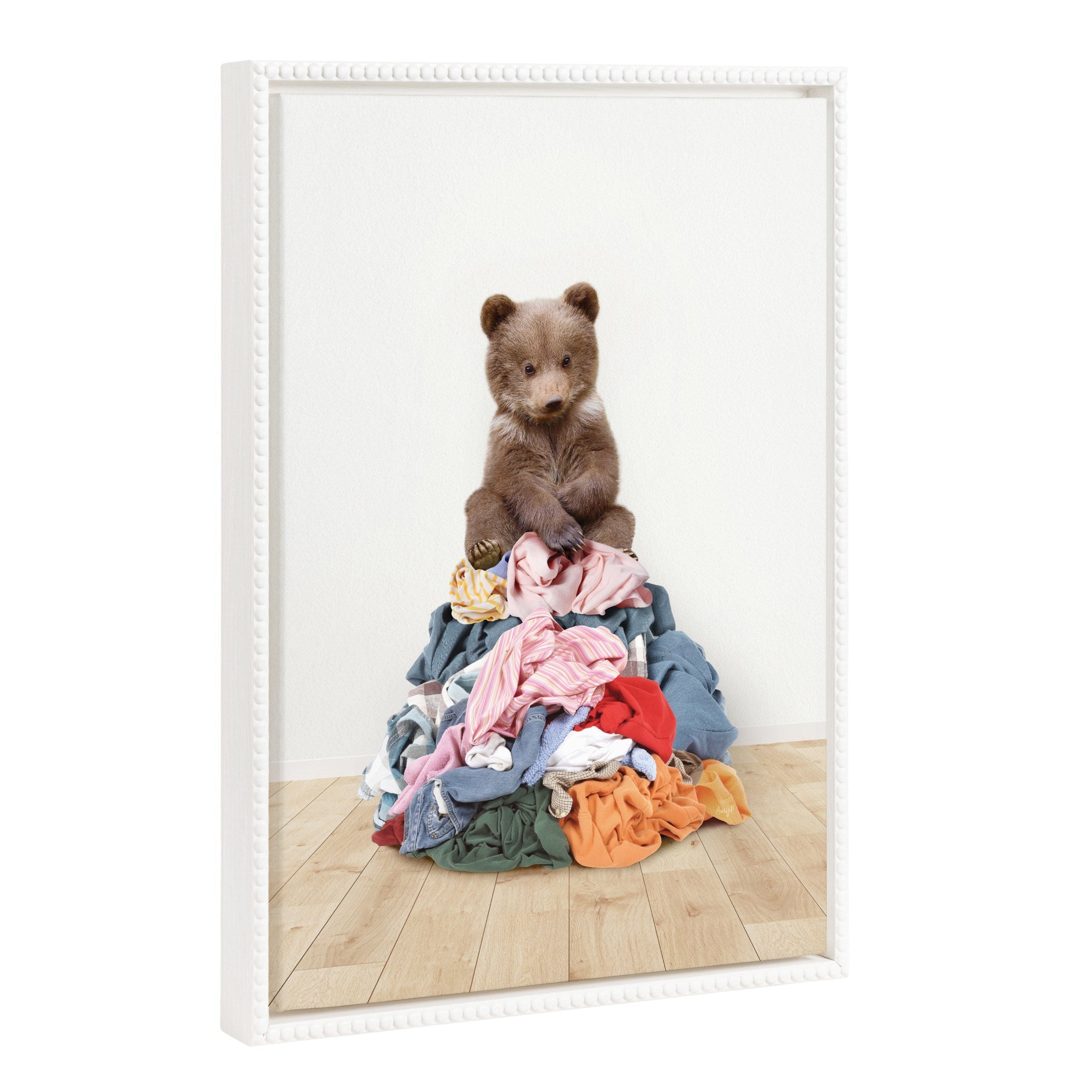 Framed canvas art of a beaded bear sitting on a laundry pile with a white background