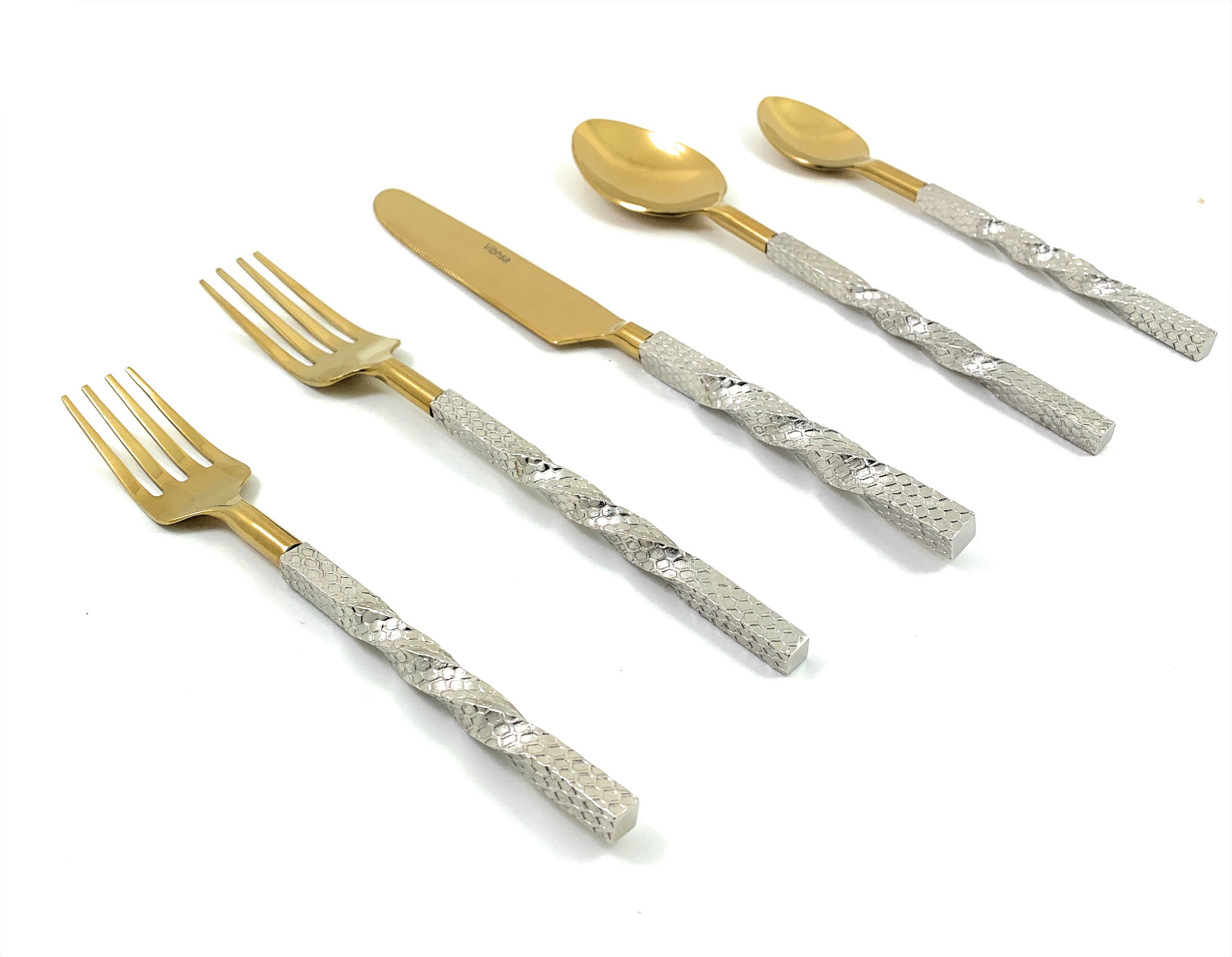 Golden stainless steel flatware set arranged on a dark wooden table